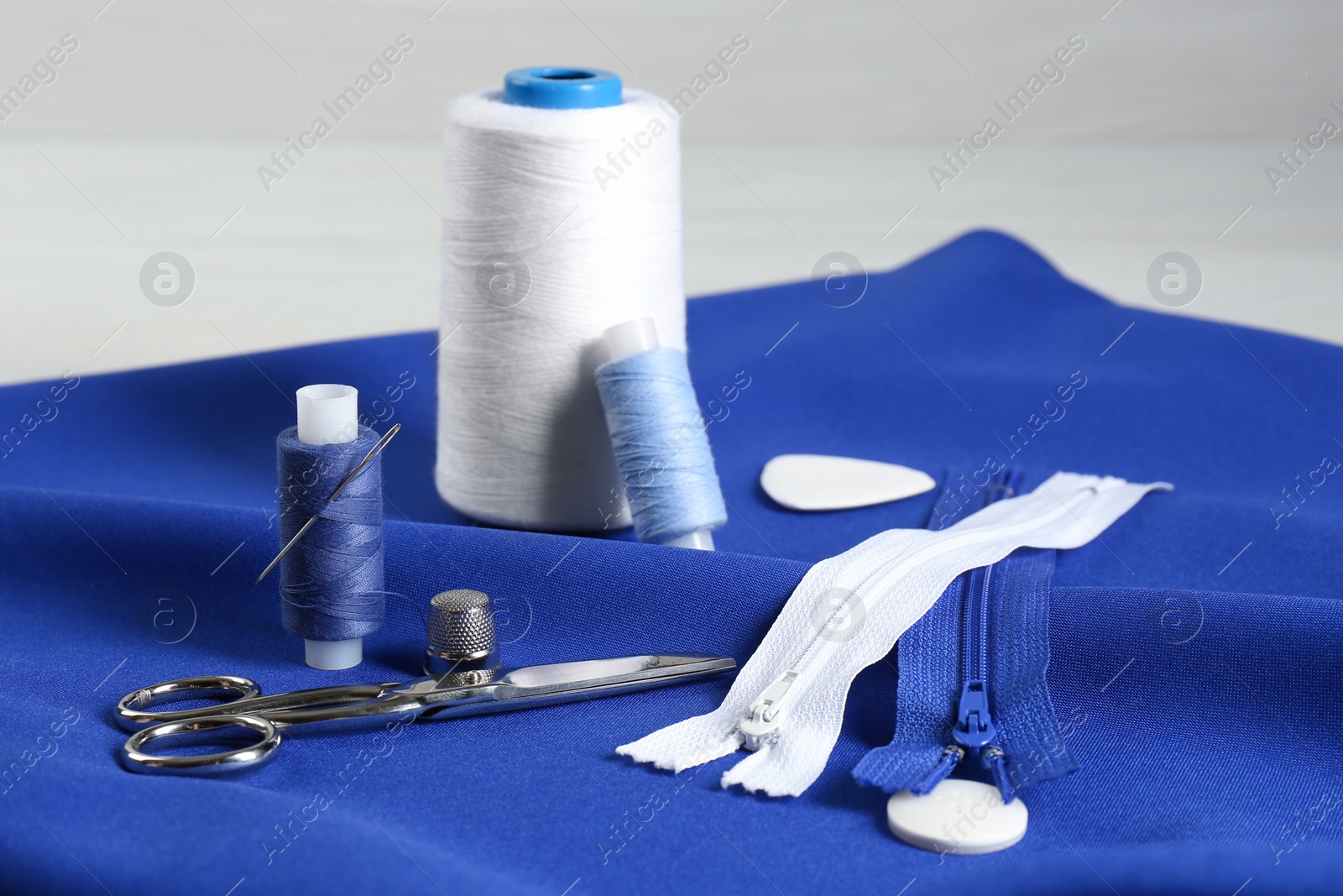 Photo of Composition with different sewing supplies on blue fabric