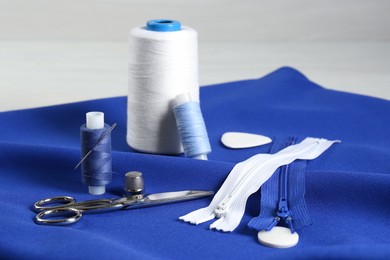 Photo of Composition with different sewing supplies on blue fabric