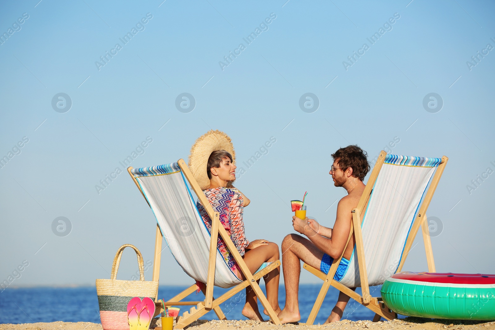 Photo of Young couple in beach chairs at seacoast