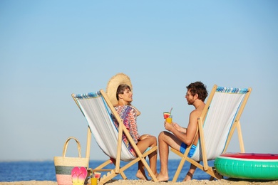 Young couple in beach chairs at seacoast