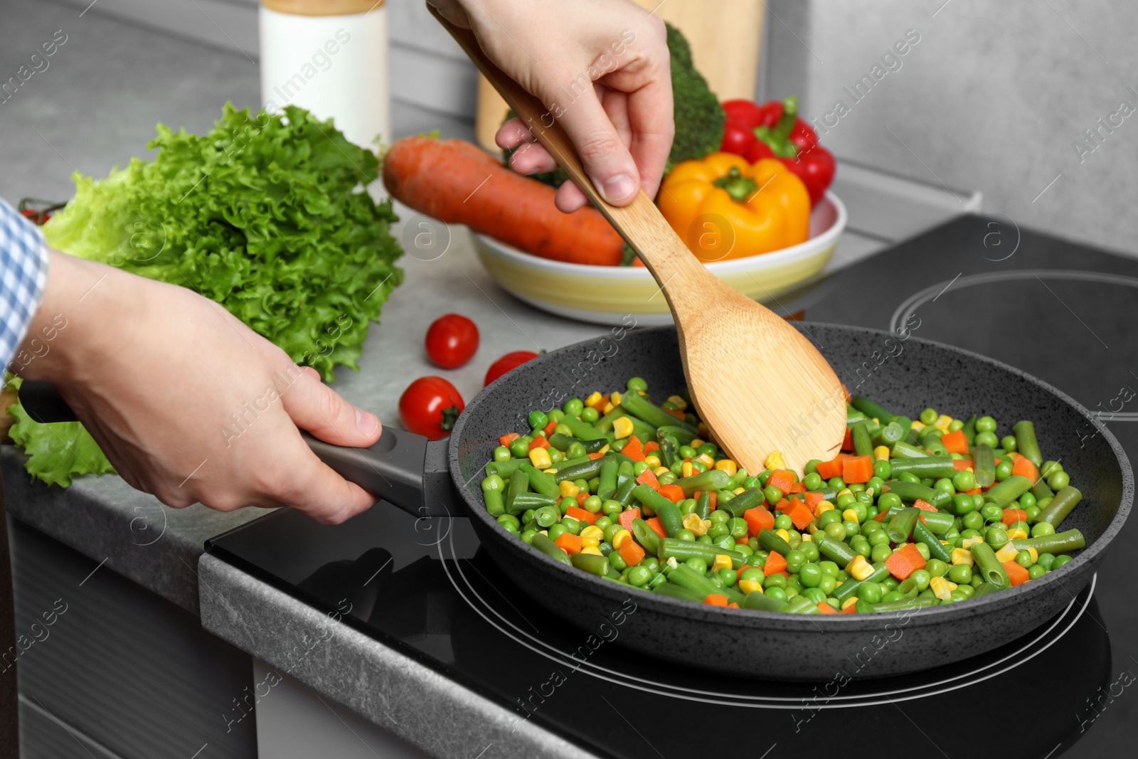 Photo of Woman cooking tasty vegetable mix in frying pan at home, closeup