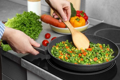 Woman cooking tasty vegetable mix in frying pan at home, closeup