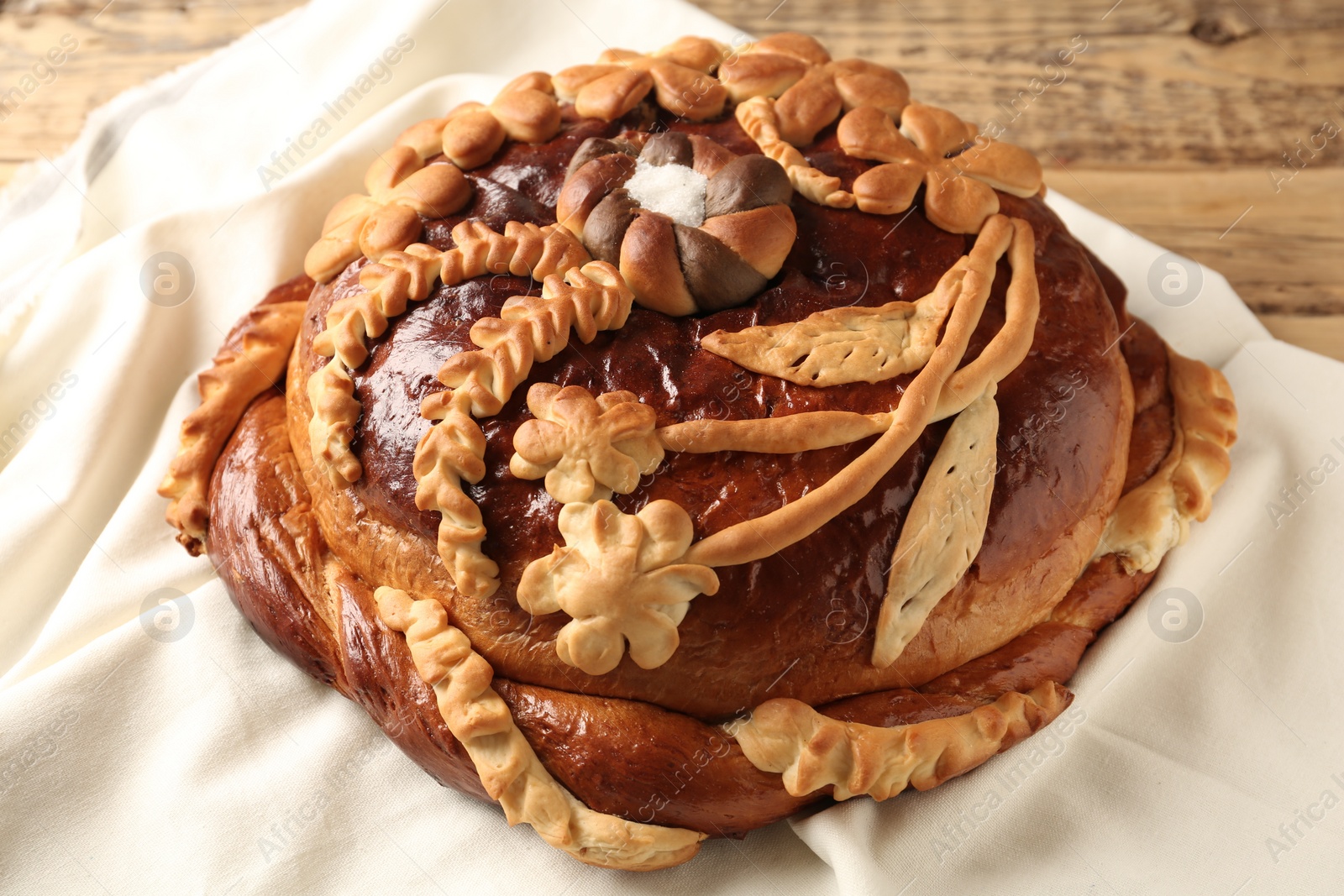 Photo of Korovai on tablecloth, closeup. Ukrainian bread and salt welcoming tradition