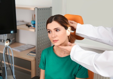 Professional otolaryngologist examining woman in clinic. Hearing disorder