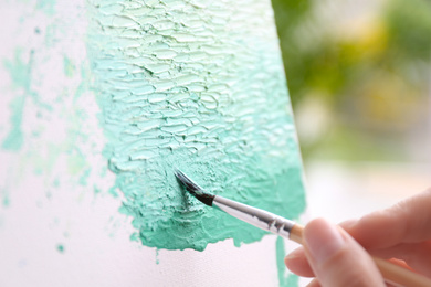 Photo of Artist painting on canvas with brush, closeup