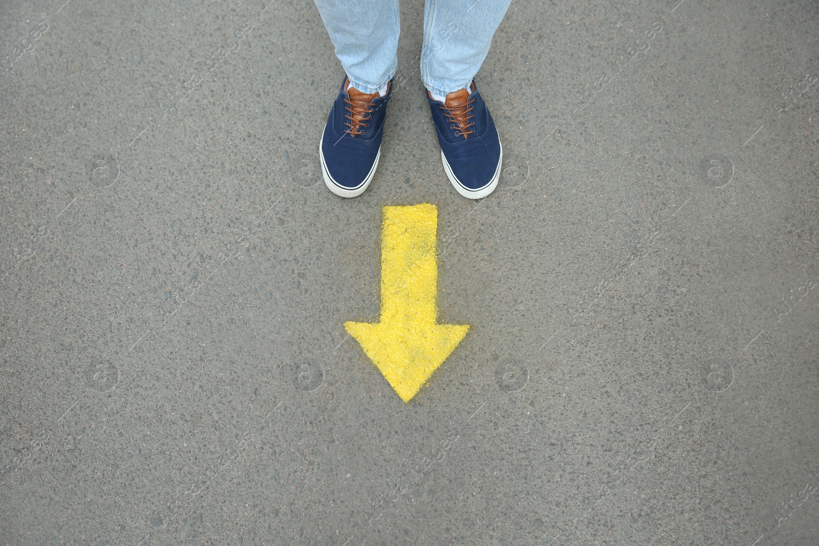 Photo of Man standing near arrow on asphalt, top view