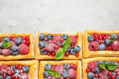 Fresh delicious puff pastry with sweet berries on grey background, flat lay. Space for text
