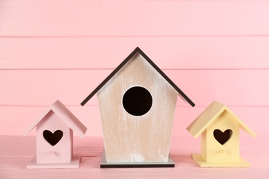Photo of Collection of handmade bird houses on pink wooden table