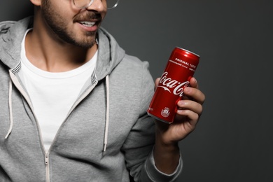 MYKOLAIV, UKRAINE - NOVEMBER 28, 2018: Young man with Coca-Cola can on dark background, closeup