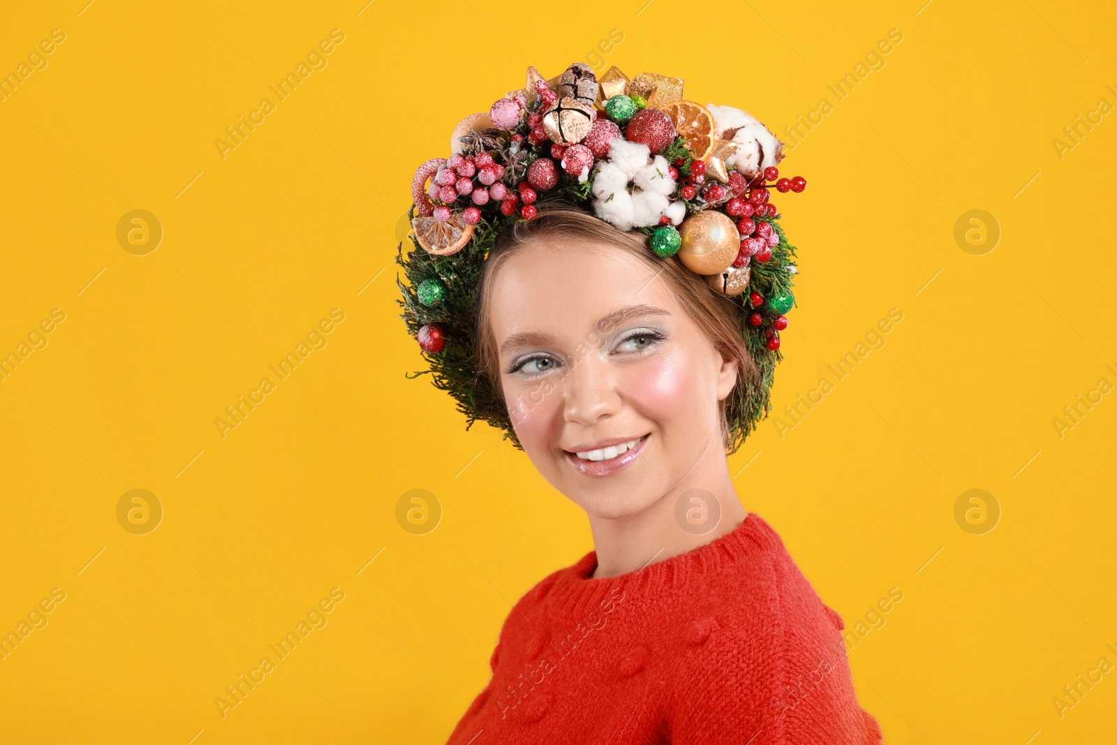 Photo of Beautiful young woman wearing Christmas wreath on yellow background