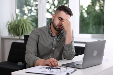 Overwhelmed man sitting at table in office