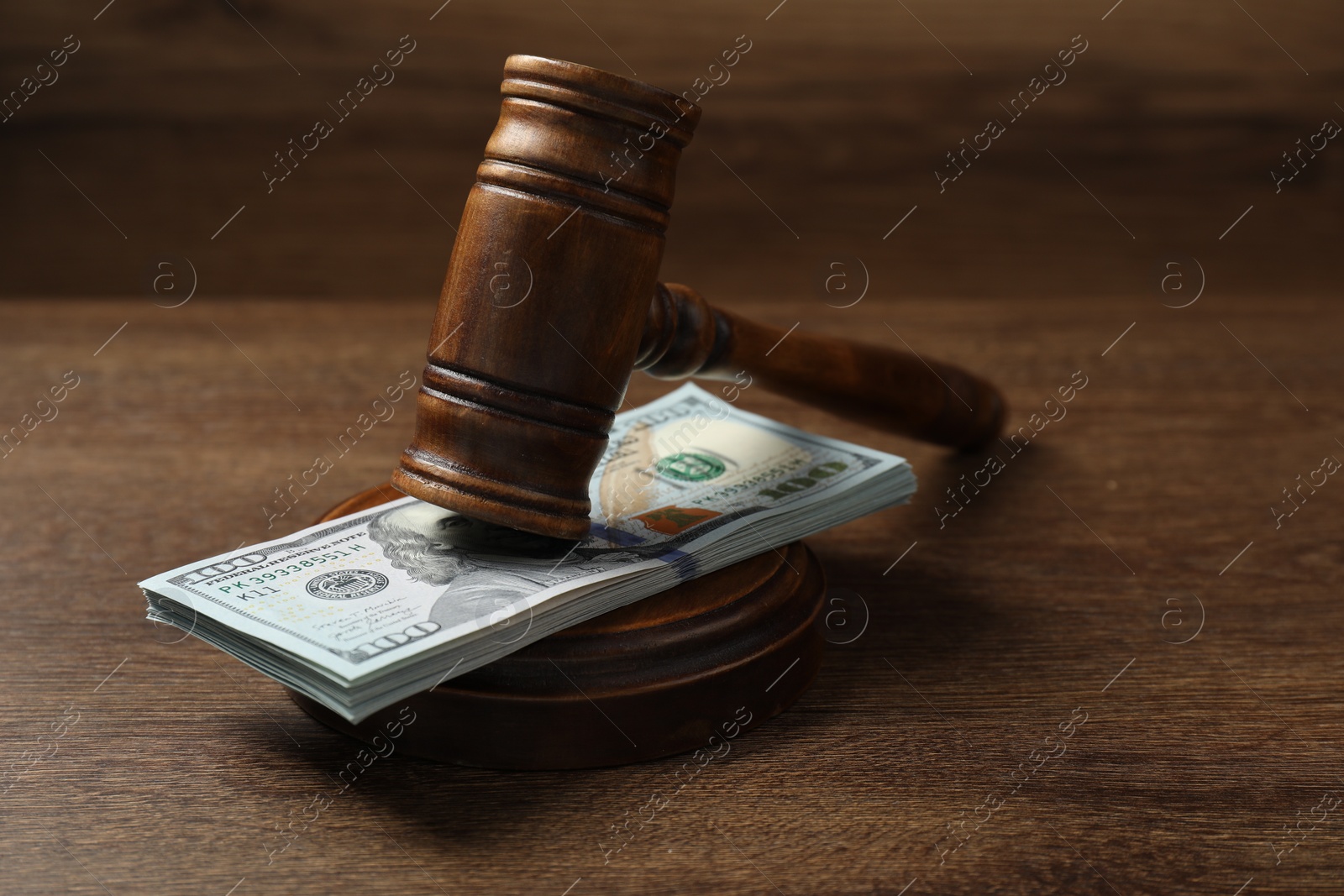 Photo of Law gavel with stack of dollars on wooden table, closeup