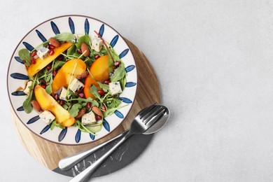 Photo of Tasty salad with persimmon, blue cheese, pomegranate and almonds served on white table, top view. Space for text