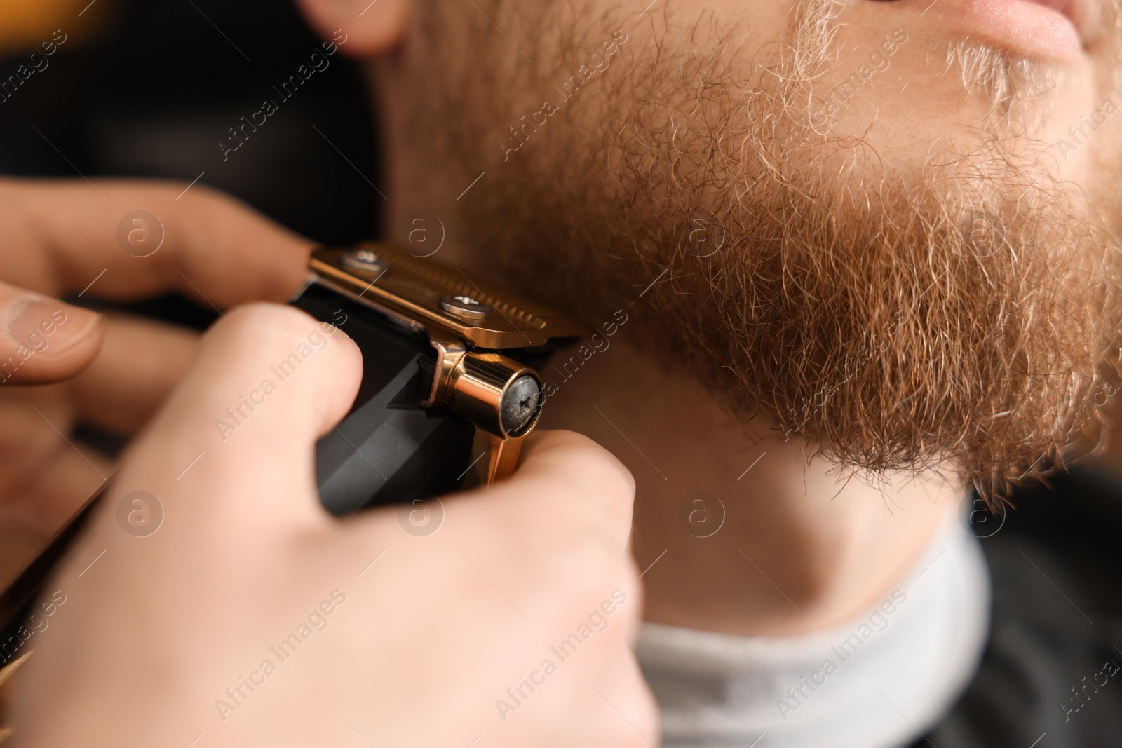 Photo of Professional hairdresser working with bearded client in barbershop, closeup