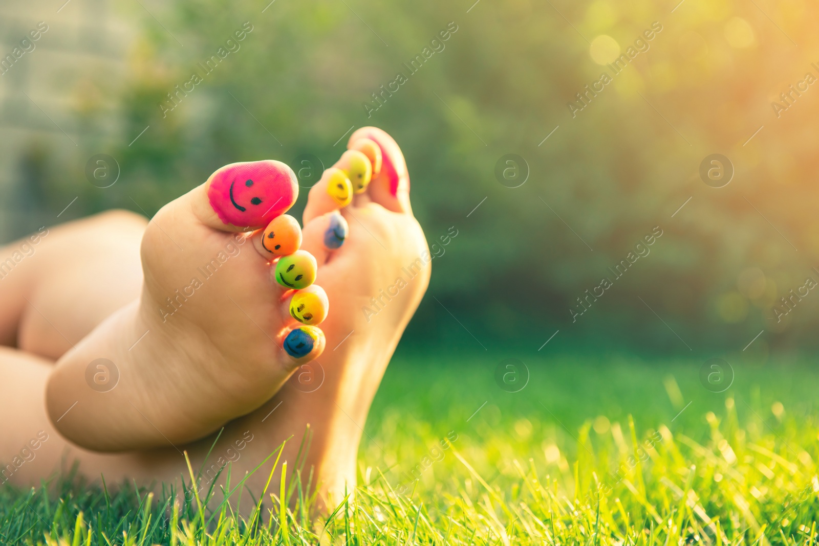 Photo of Teenage girl with smiling faces drawn on toes outdoors, closeup. Space for text