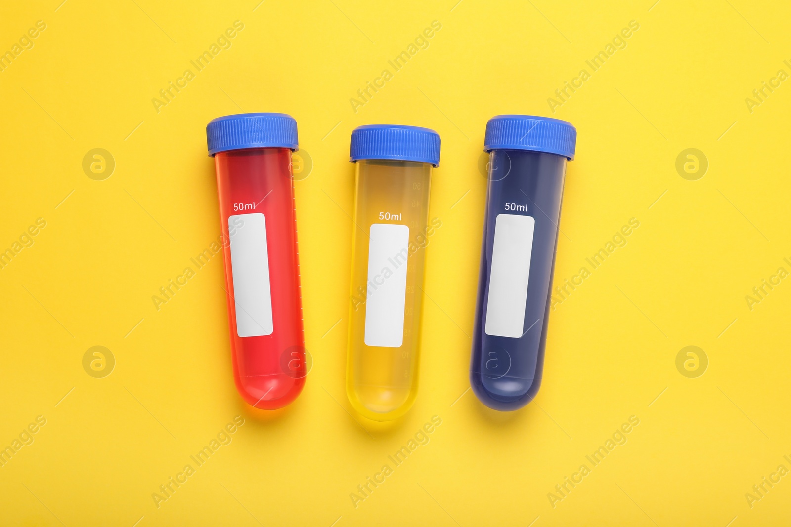 Photo of Test tubes with colorful liquids on yellow background, flat lay. Kids chemical experiment set