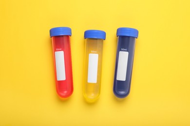 Photo of Test tubes with colorful liquids on yellow background, flat lay. Kids chemical experiment set