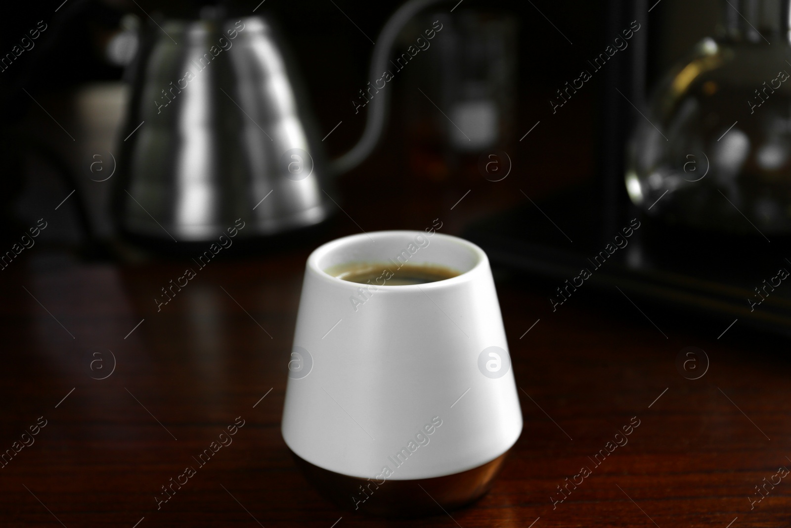 Photo of Cup with coffee and vacuum maker on wooden table in cafe