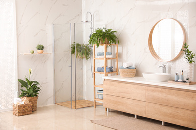 Photo of Stylish bathroom interior with countertop, shower stall and houseplants. Design idea