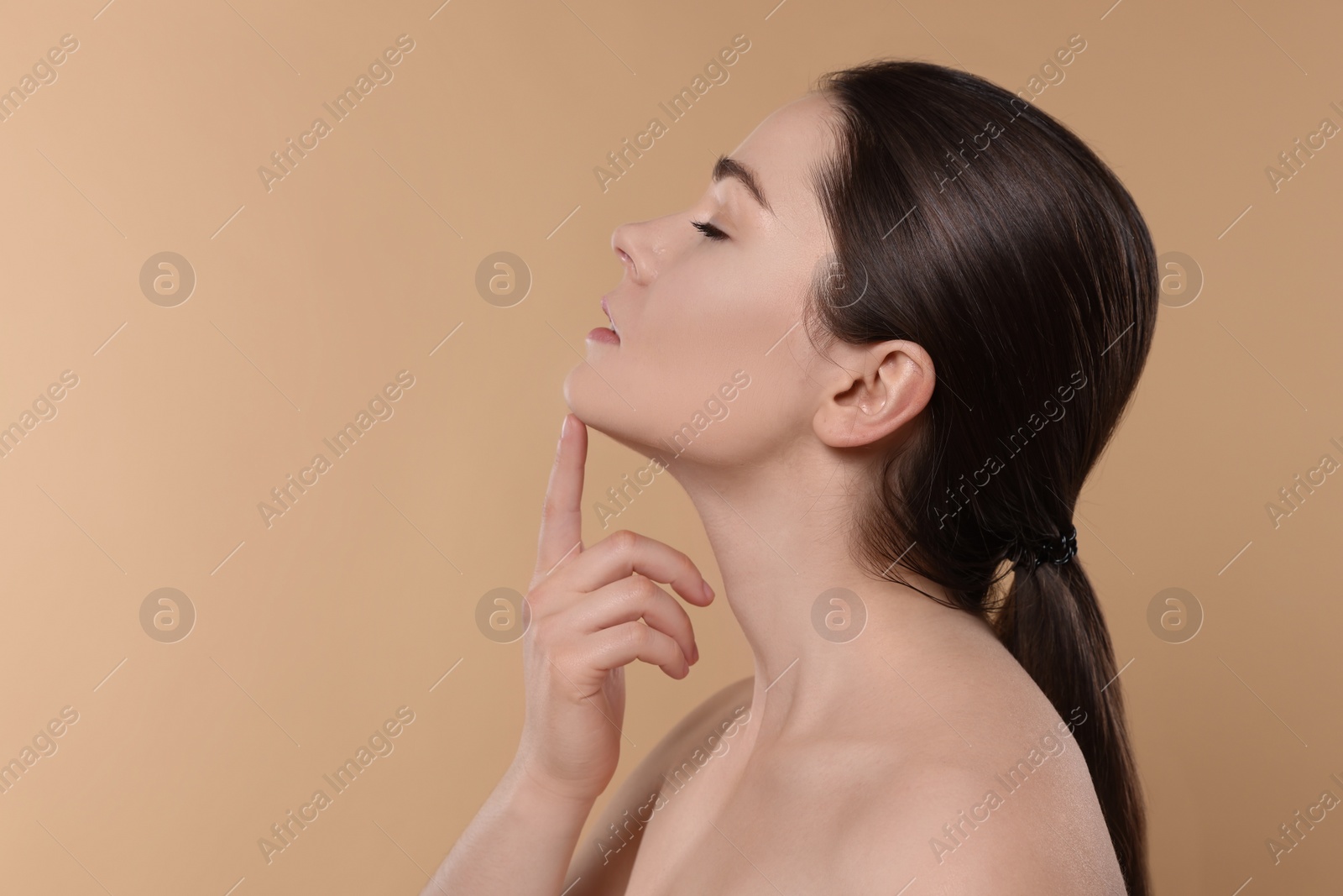 Photo of Young woman massaging her face on beige background. Space for text