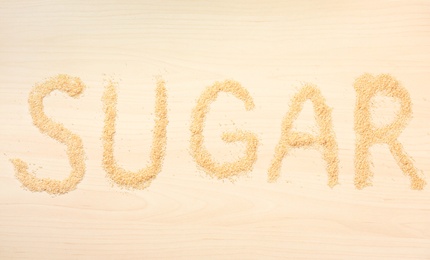 Word SUGAR on wooden background