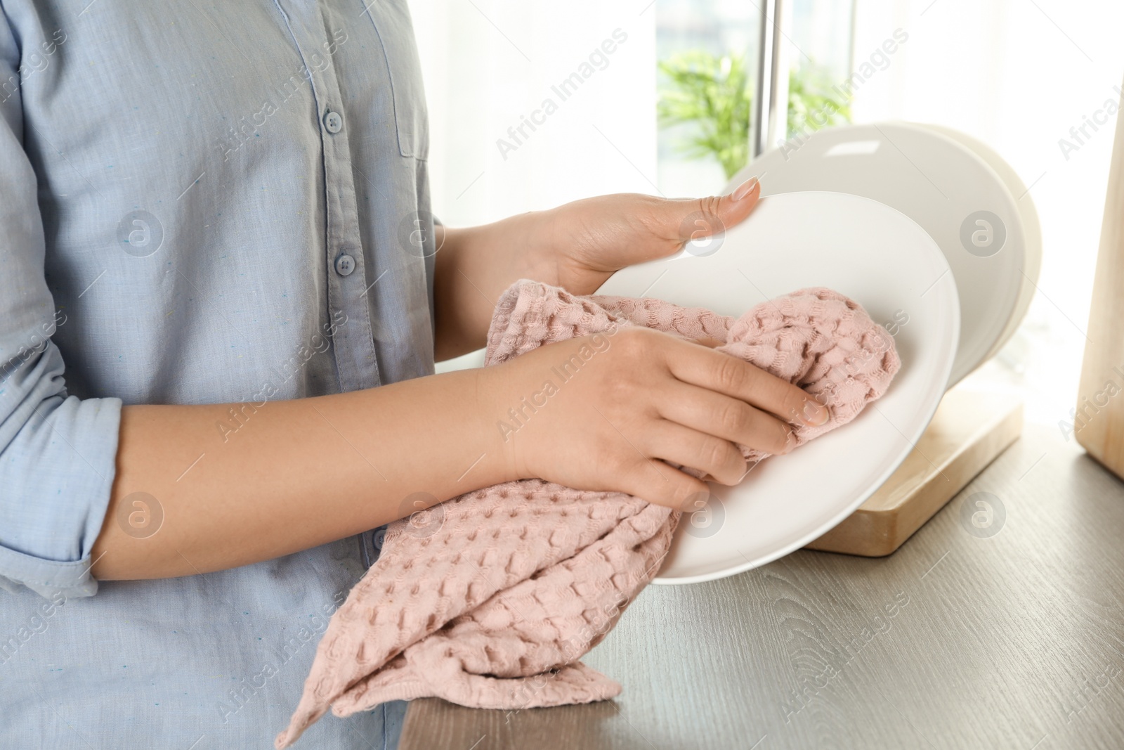 Photo of Woman wiping plate with kitchen towel indoors, closeup