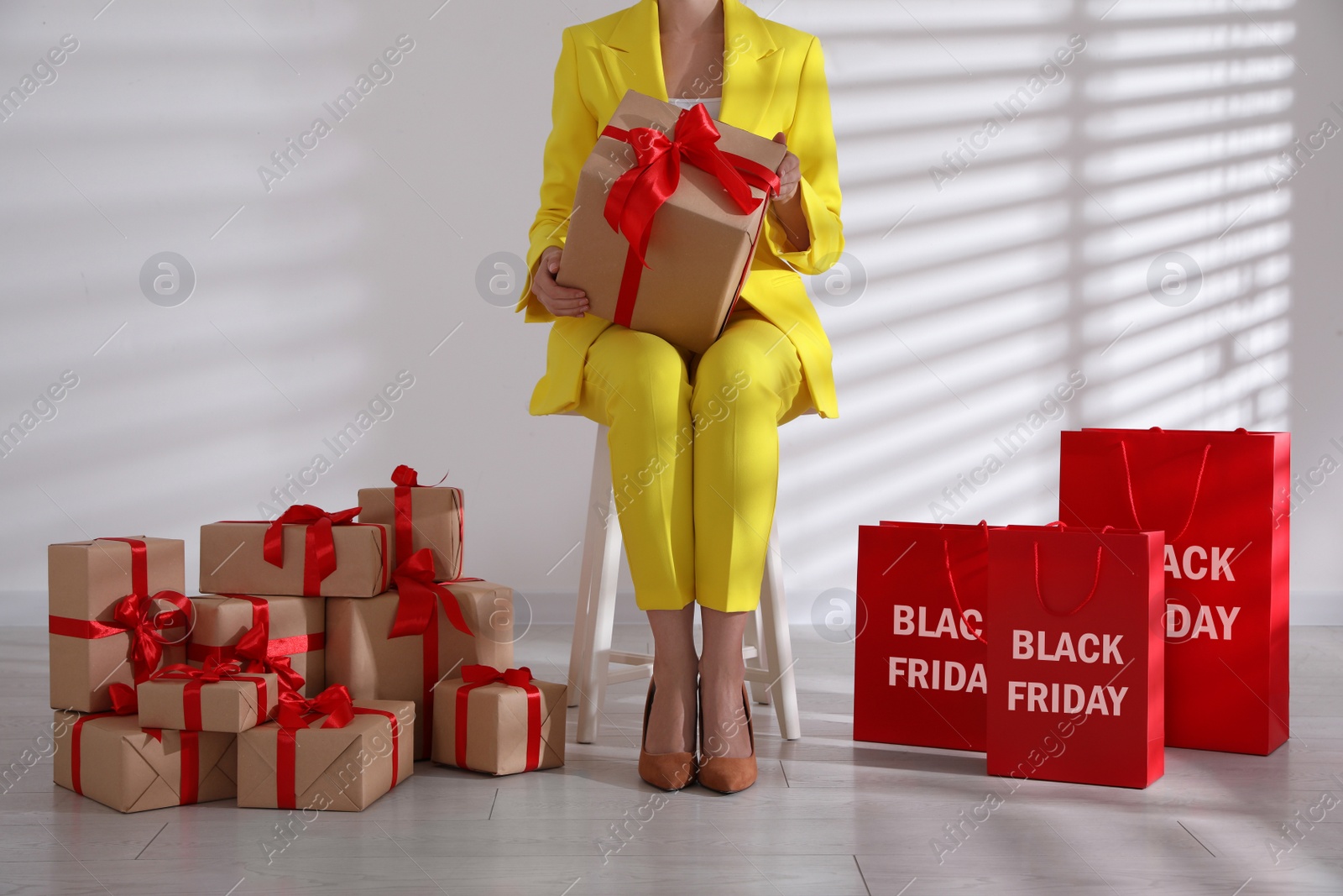Photo of Woman with gift boxes sitting on stool, closeup. Black Friday
