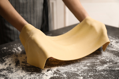 Photo of Woman with dough at grey table, closeup. Making pasta