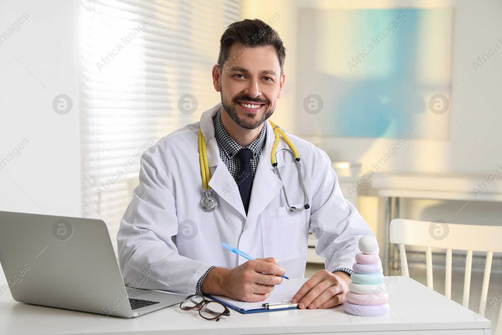 Photo of Pediatrician with stethoscope at table in clinic