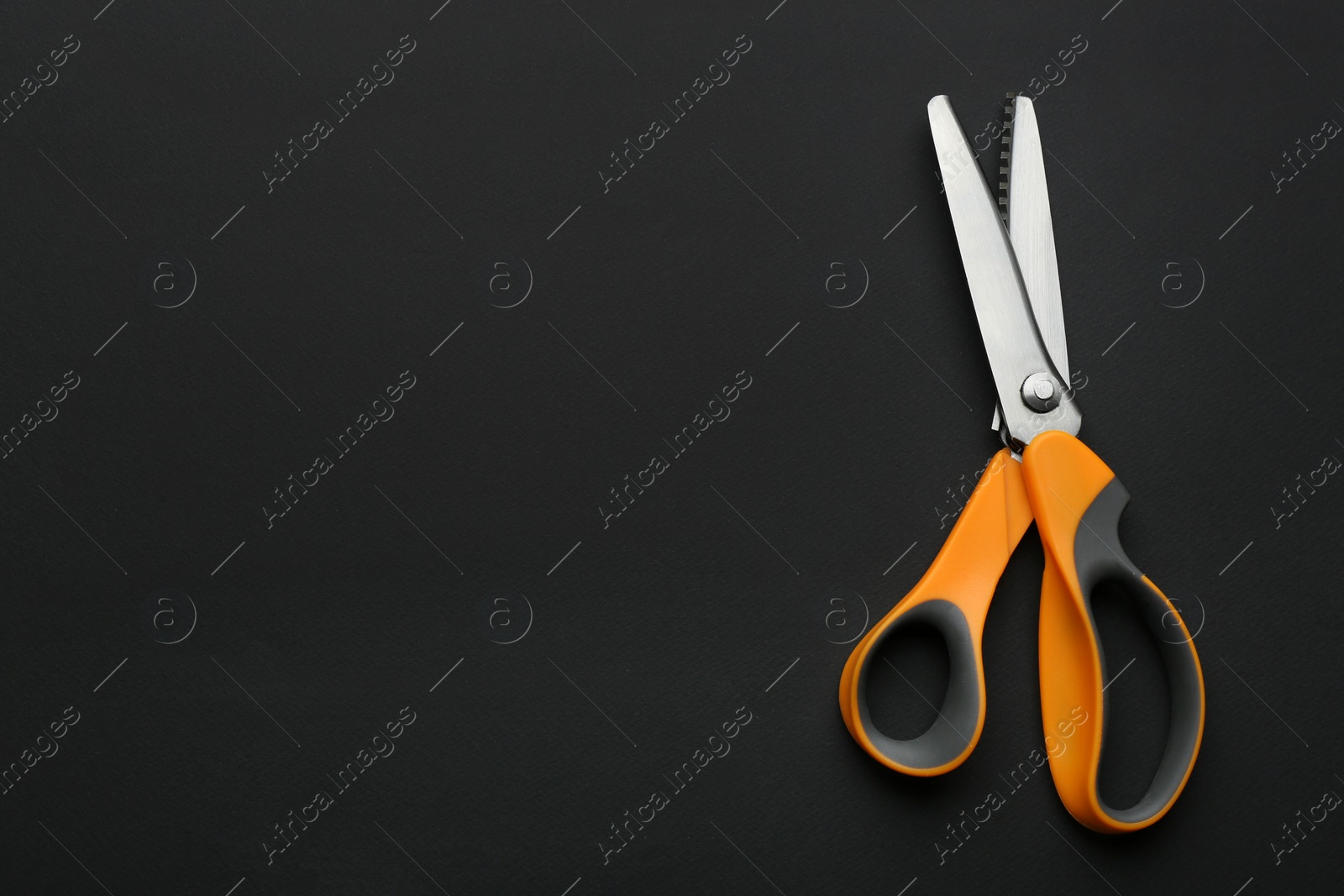 Photo of Pair of sharp scissors on dark background, top view. Space for text