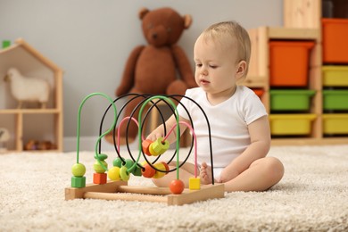 Photo of Children toys. Cute little boy playing with bead maze on rug at home