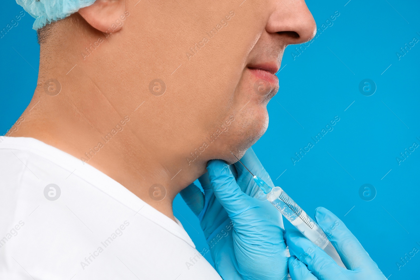 Photo of Mature man with double chin receiving injection on blue background, closeup