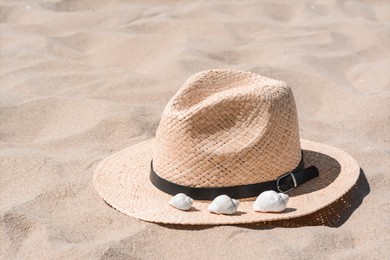 Photo of Straw hat with seashells on sandy beach