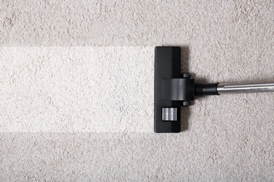 Photo of Vacuum cleaner on carpet indoors, closeup. Cleaning service