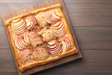 Photo of Freshly baked apple pie with nuts on wooden table, top view