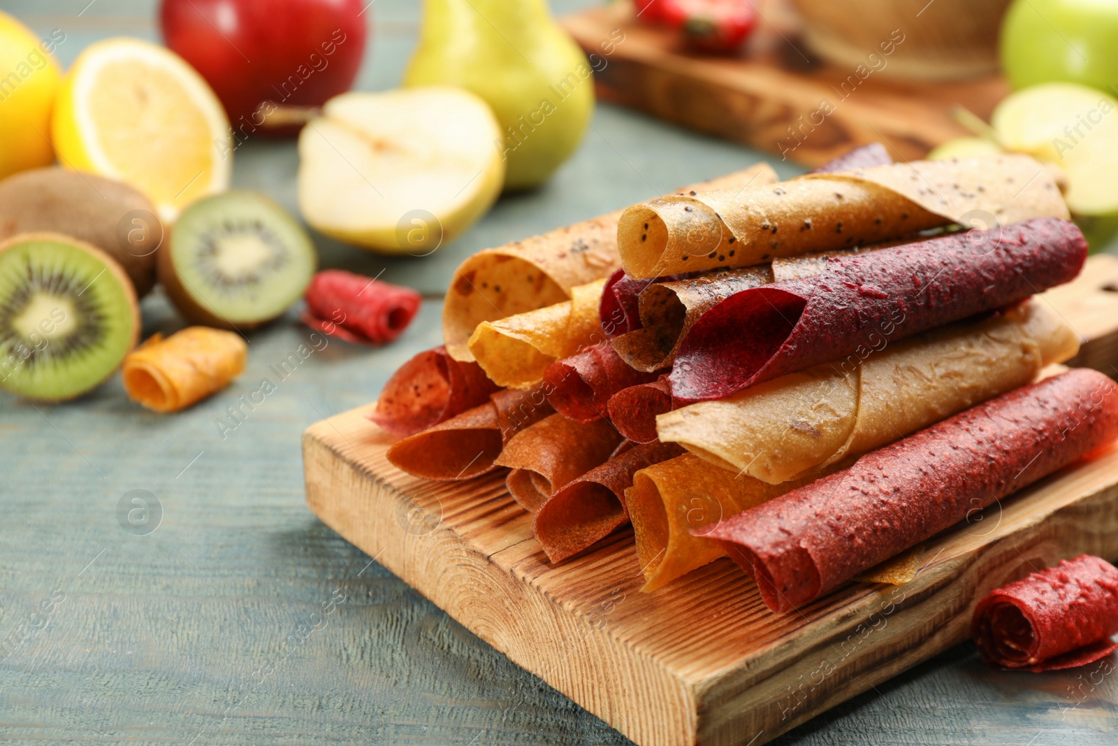 Photo of Composition with delicious fruit leather rolls on blue wooden table. Space for text