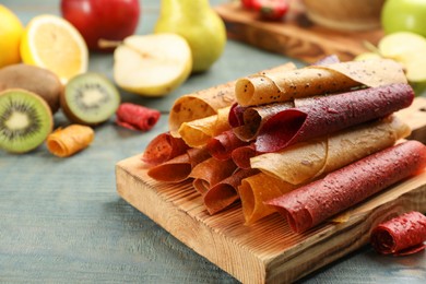 Composition with delicious fruit leather rolls on blue wooden table. Space for text