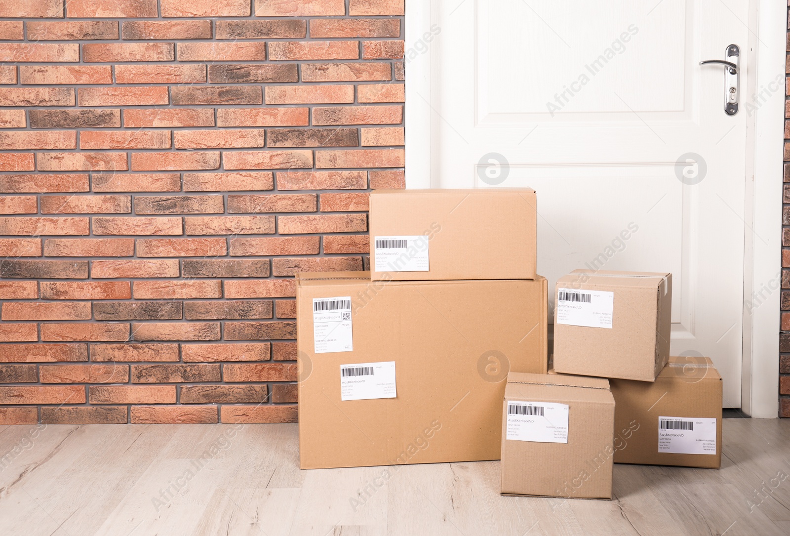 Photo of Cardboard parcel boxes on floor near apartment entrance. Mockup for design