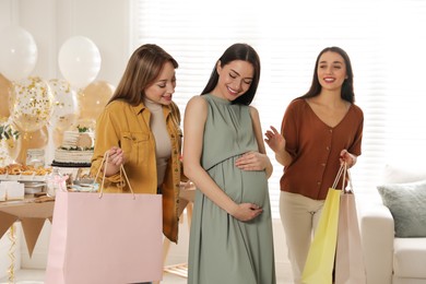 Happy pregnant woman spending time with friends at baby shower party