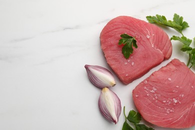 Photo of Raw tuna fillets with parsley and shallot on white marble table, flat lay. Space for text