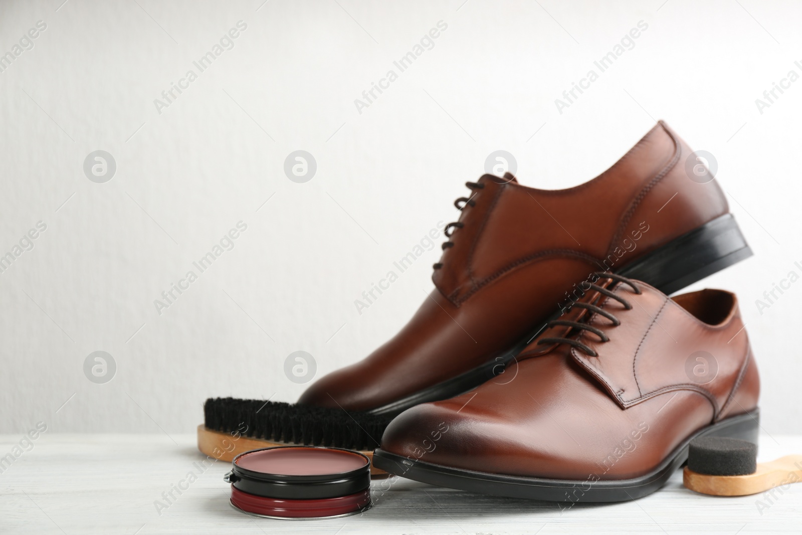 Photo of Shoe care products and footwear on white table. Space for text