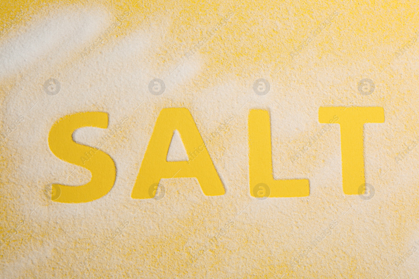 Photo of Word SALT on yellow background, top view