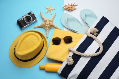 Stylish bag with beach accessories on color background, flat lay