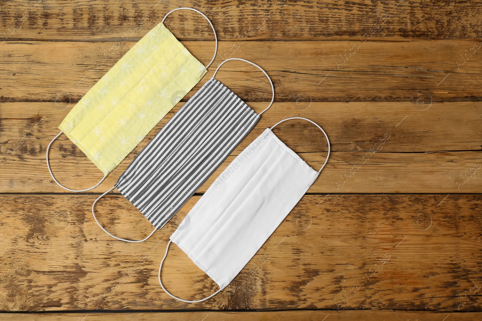 Photo of Homemade protective face masks on wooden table, flat lay. Space for text