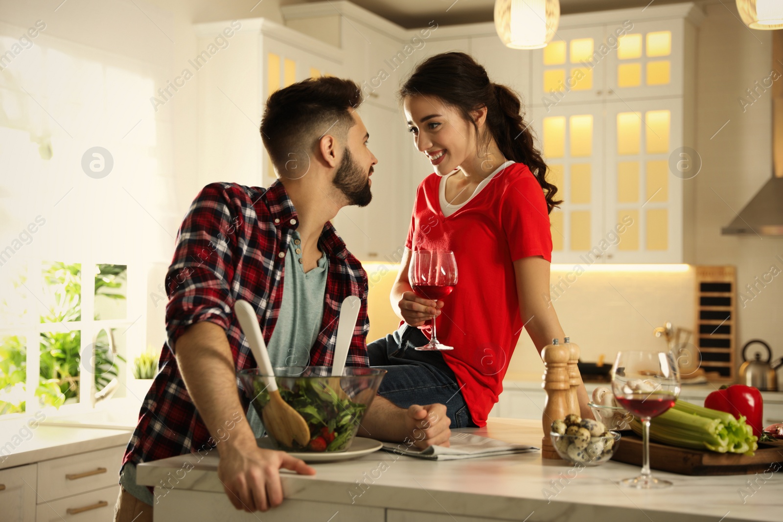 Photo of Lovely young couple cooking salad together in kitchen