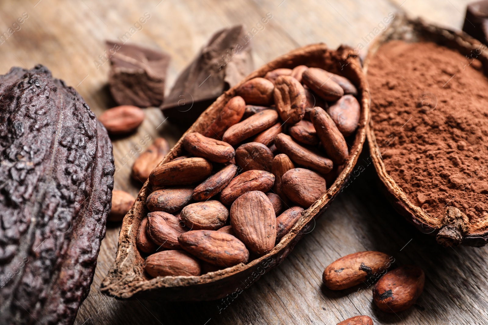 Photo of Cocoa pods with beans and powder on wooden table