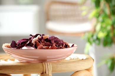 Photo of Aromatic potpourri of dried flowers in bowl on wicker table indoors