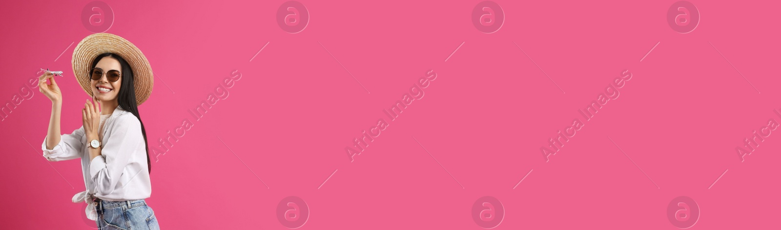 Photo of Happy female tourist with toy plane on pink background. Space for text