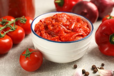 Delicious lecho in bowl and fresh ingredients on light grey table, closeup