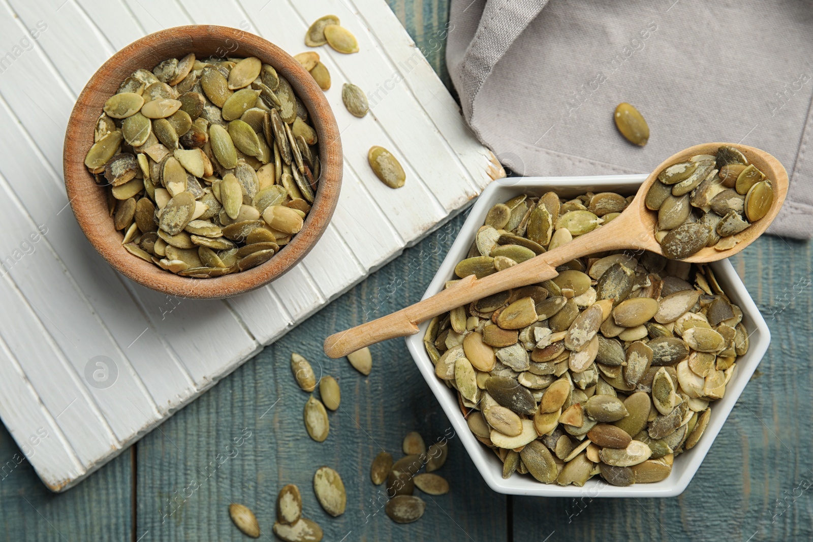 Photo of Flat lay composition with raw pumpkin seeds on blue wooden table